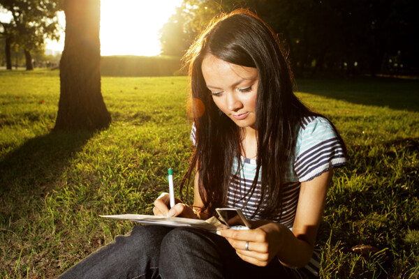 坐在草地上的写字女孩图片