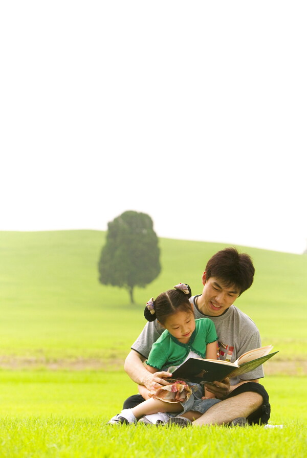 小孩子和爸爸坐在草地上看书图片