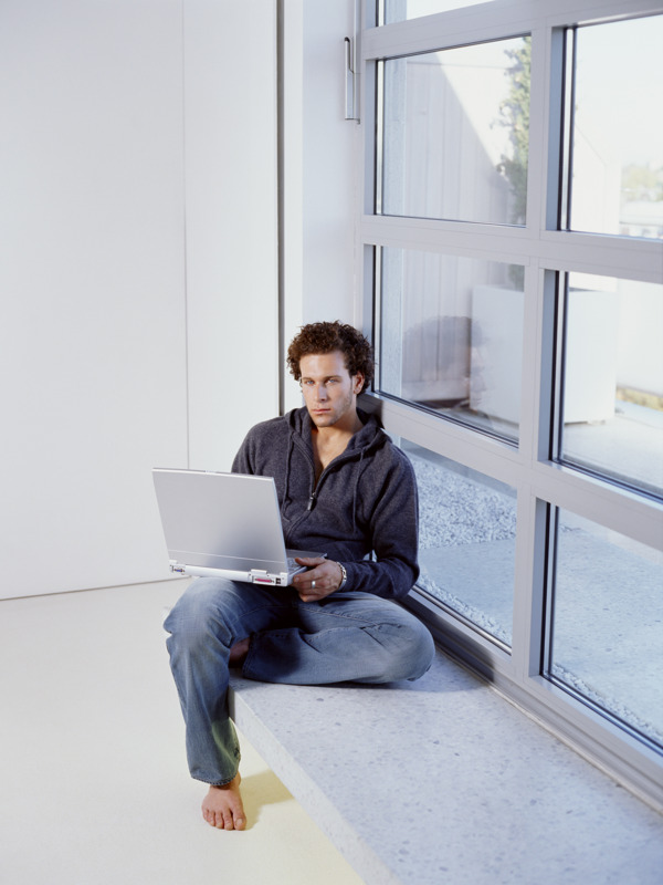 坐在窗台上玩电脑的男人图片